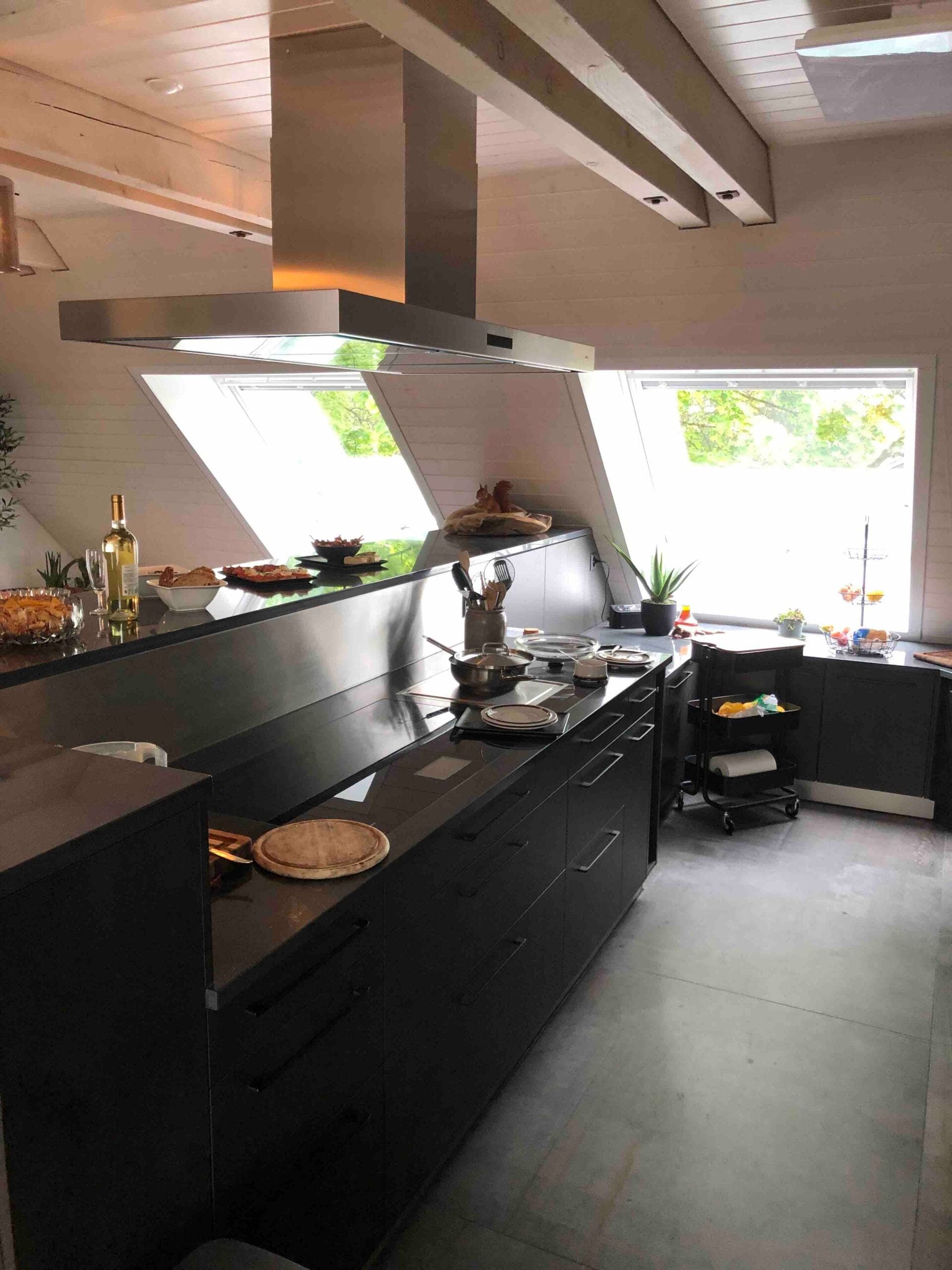 Dunkle Küchenzeile unter der Dachschräge mit Inselhaube, Dachwohnung Zürich