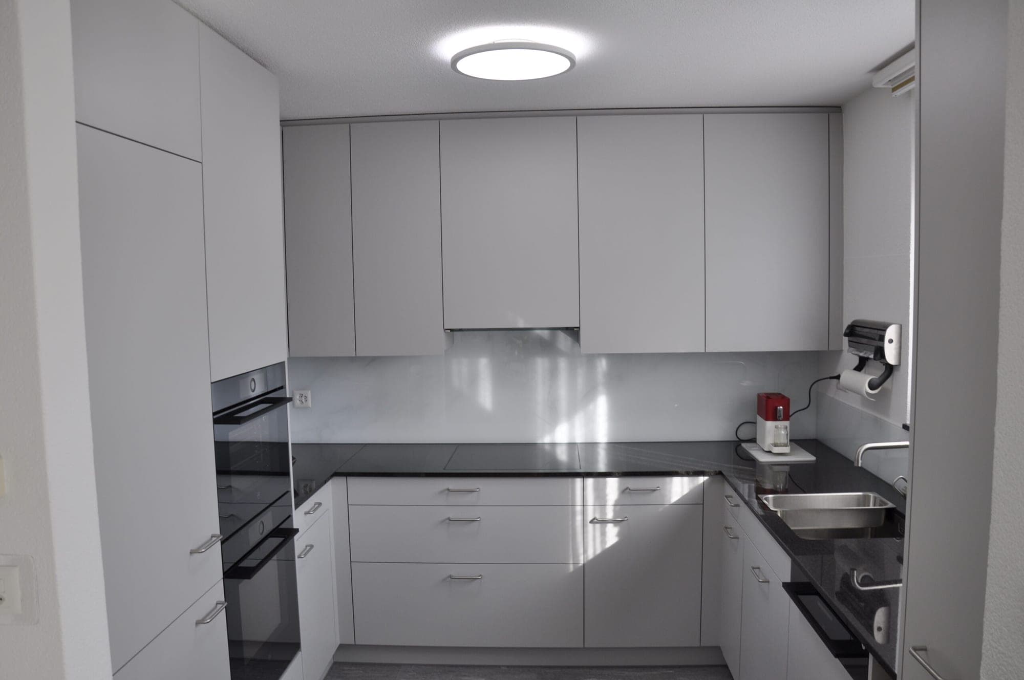 Wohnung Kloten – Hellgrau & Glasrückwand